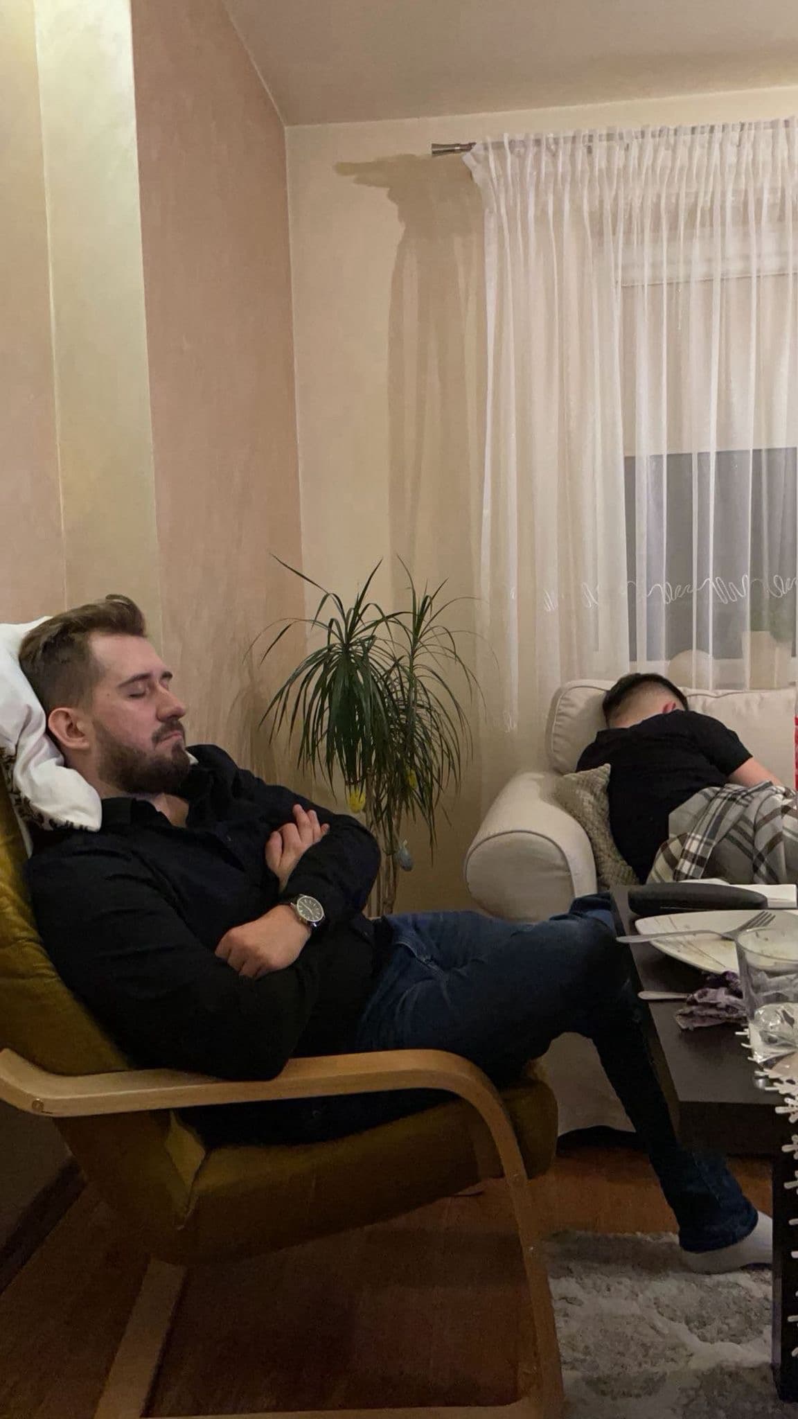 Dwóch śpiących mężczyzn — jeden w fotelu, drugi na kanapie