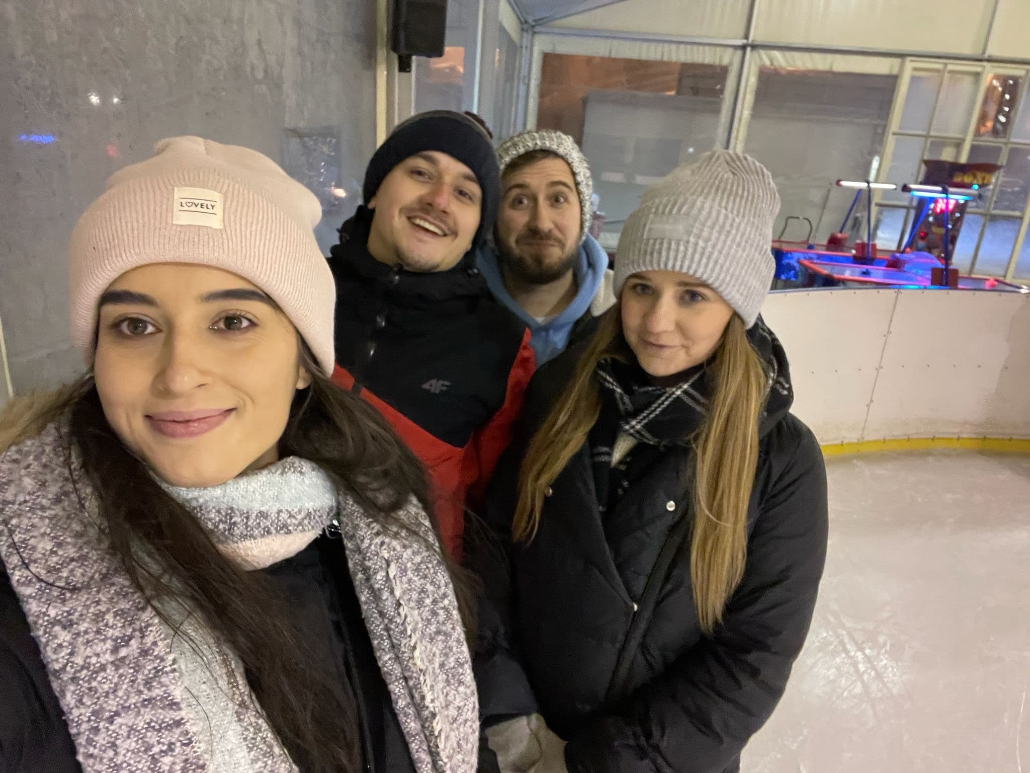 Selfie czwórki znajomych w czapkach na lodowisku